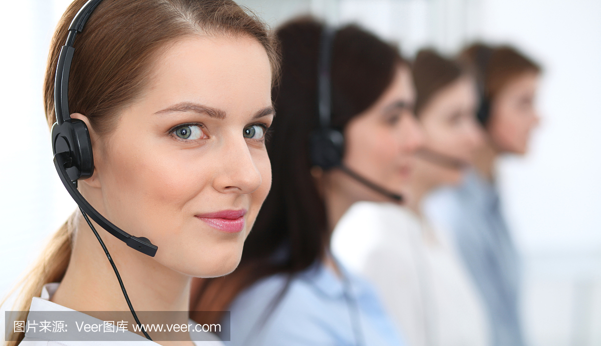呼叫中心。美丽开朗微笑的操作员戴着耳机咨询客户。客户服务的经营理念。